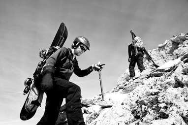 Snowboarder Climbing up a rocky ridge to ride down.