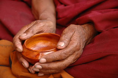 Hands of a Tibetan monk holding a wooden tea cup.  Lama Yuru, Ladakh, India